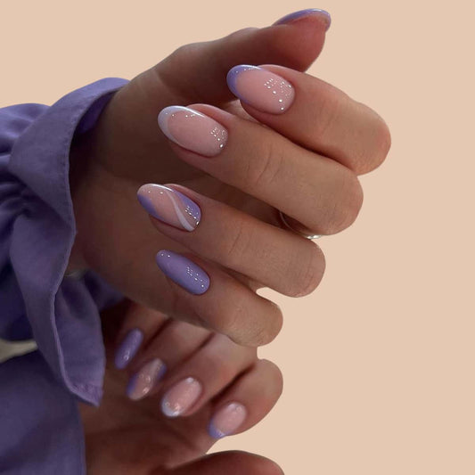 A set of press-on nails in pastel purple with rhinestone accents, displayed on a hand.