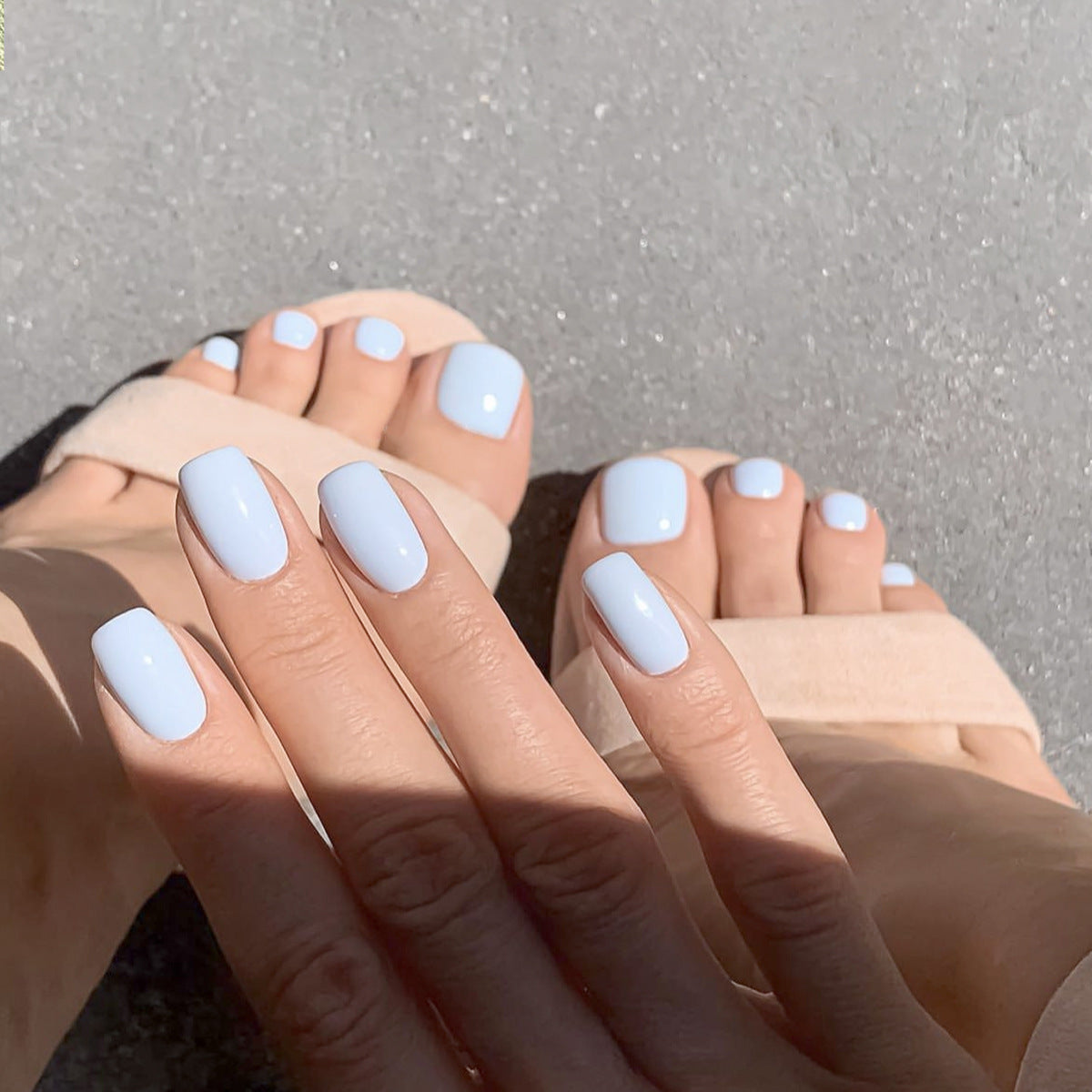 Close-up of feet with light blue nail polish on a neutral background