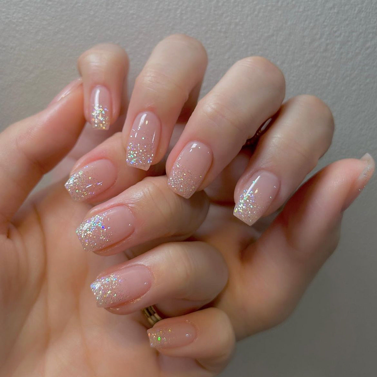 Hand with glittery nail polish on a neutral background