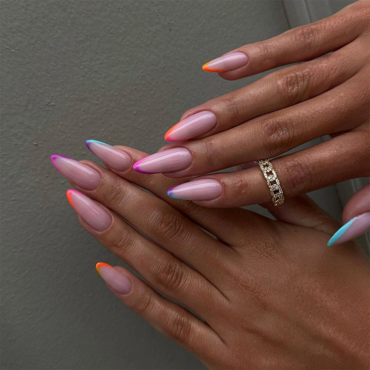 A set of long, almond-colored press-on nails with multicolored French tips.