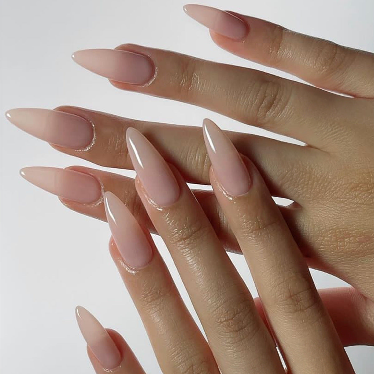 A pair of long almond beige press-on nails with a high gloss finish.