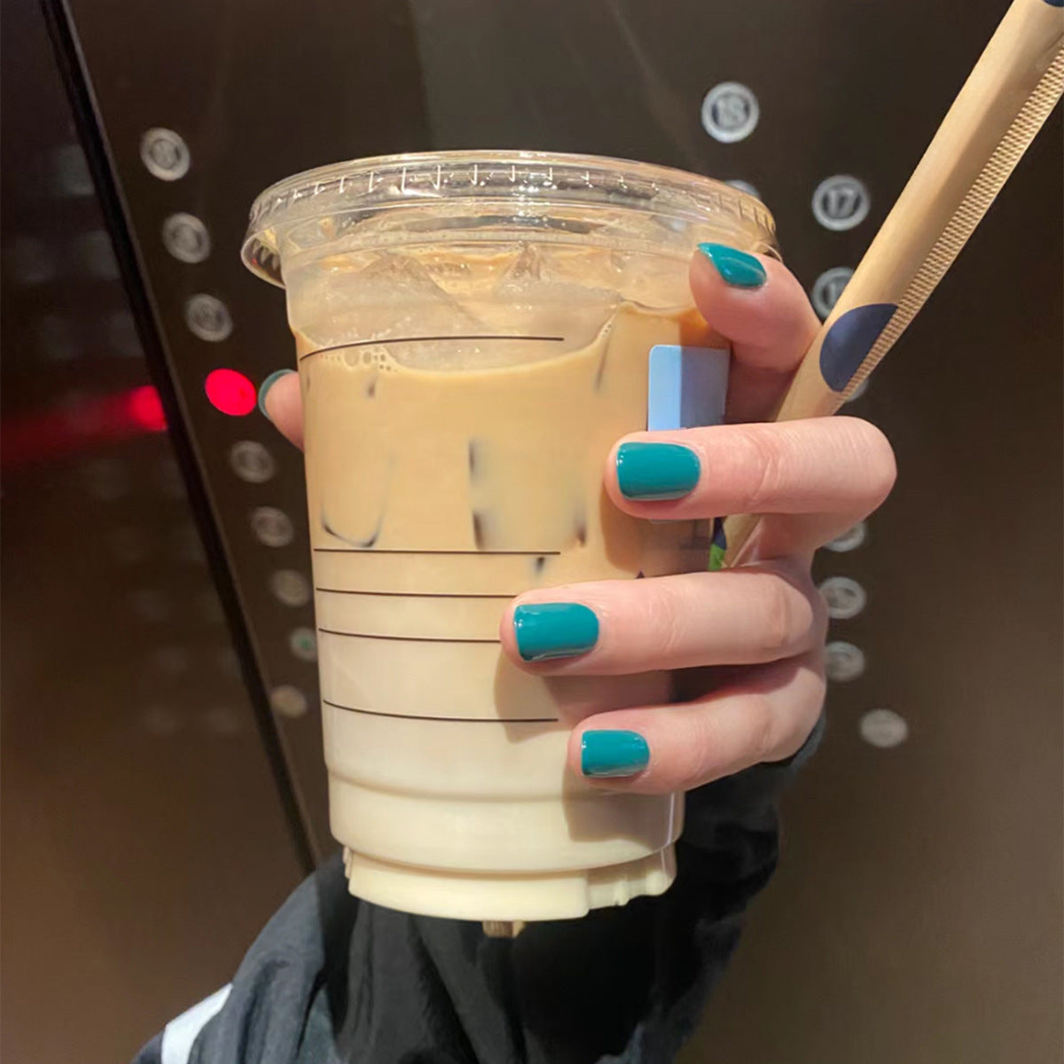 Hand holding a cup of iced coffee with a straw, blurred background