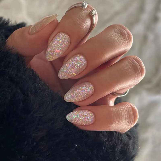 A person's hand with medium-sized, almond-colored press-on nails featuring a multicolor glitter design.