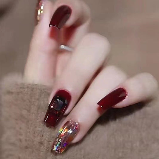 Close-up of a hand with burgundy nail polish on a neutral background