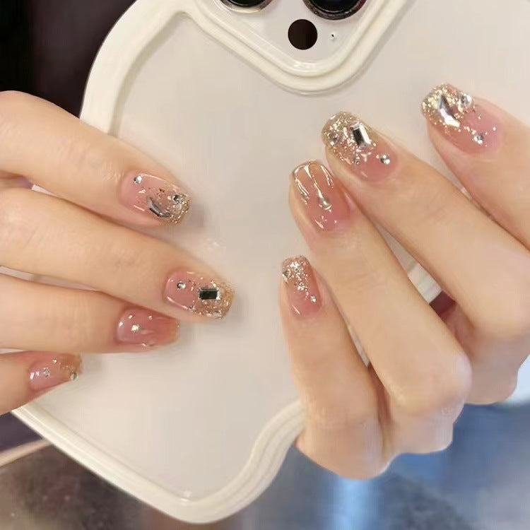 A set of press-on nails featuring a square shape with beige color and glitter accents on the tips.