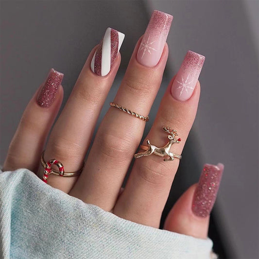 Close-up of a hand with glittery pink nails and decorative rings on a neutral background
