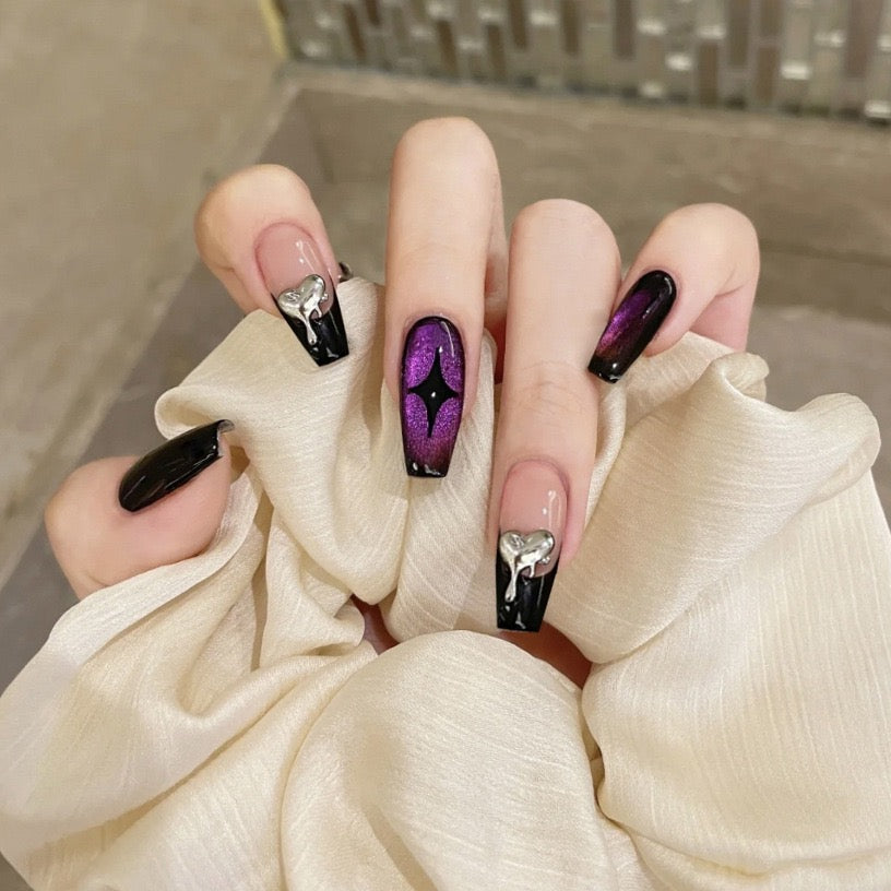 Close-up of a hand with stylish black and purple nail design holding a white fabric.