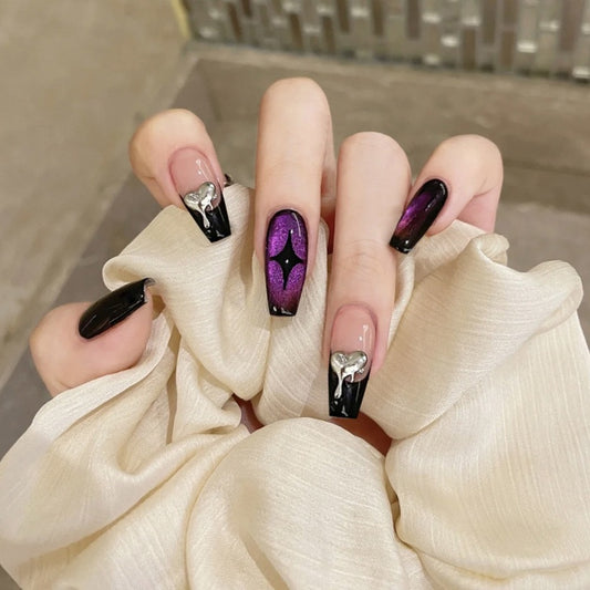 Close-up of a hand with stylish black and purple nail design holding a white fabric.