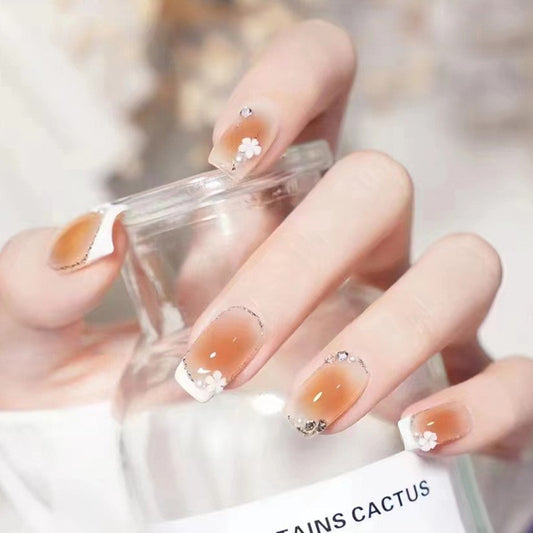 Close-up of a hand with orange nail polish holding a clear container.