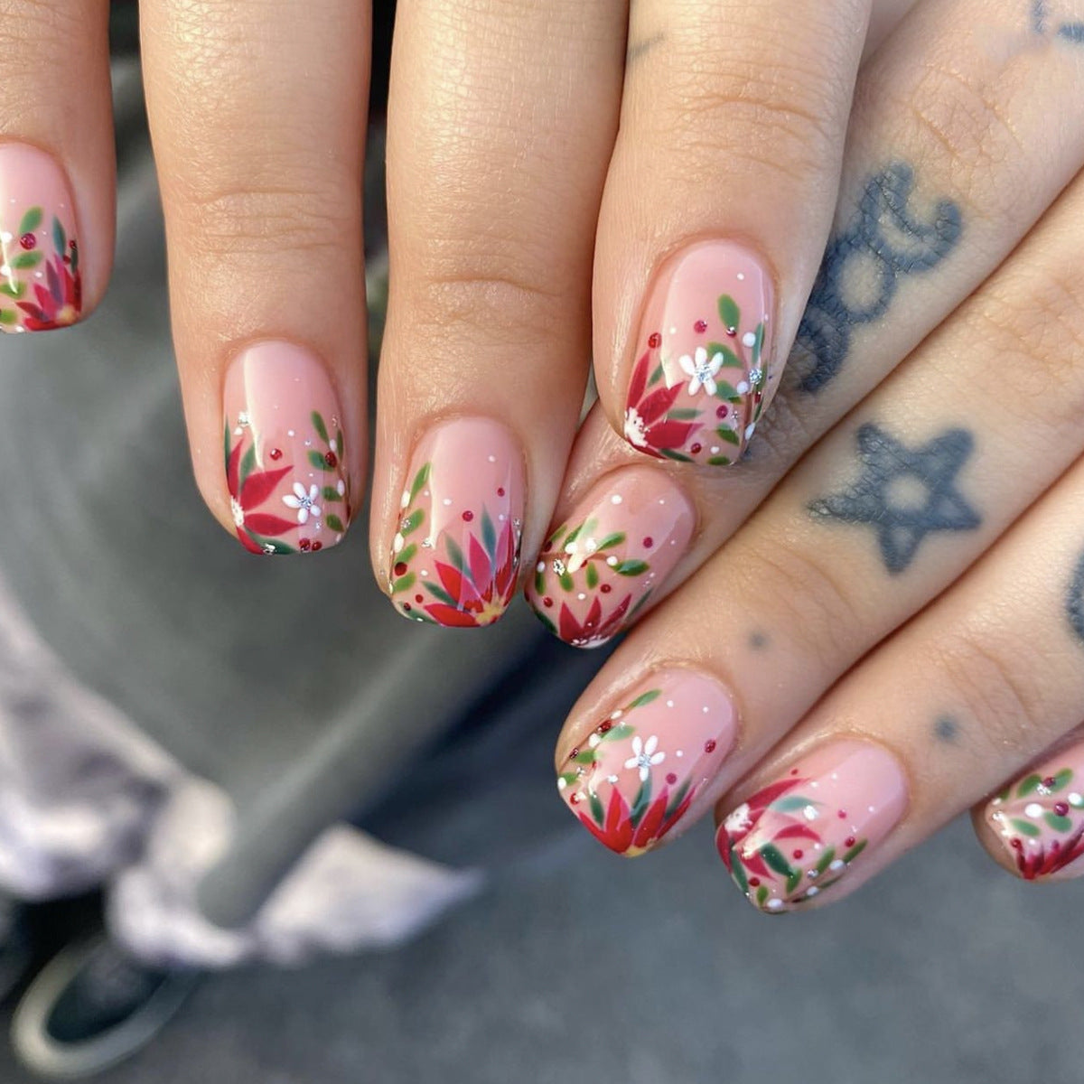 Close-up of hands with floral nail design on a blurred background