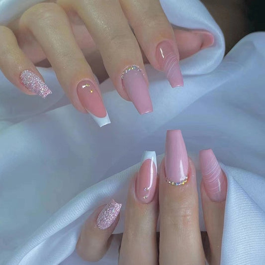 A set of press-on nails in medium coffin shape, featuring a pink glitter design with a white tip.