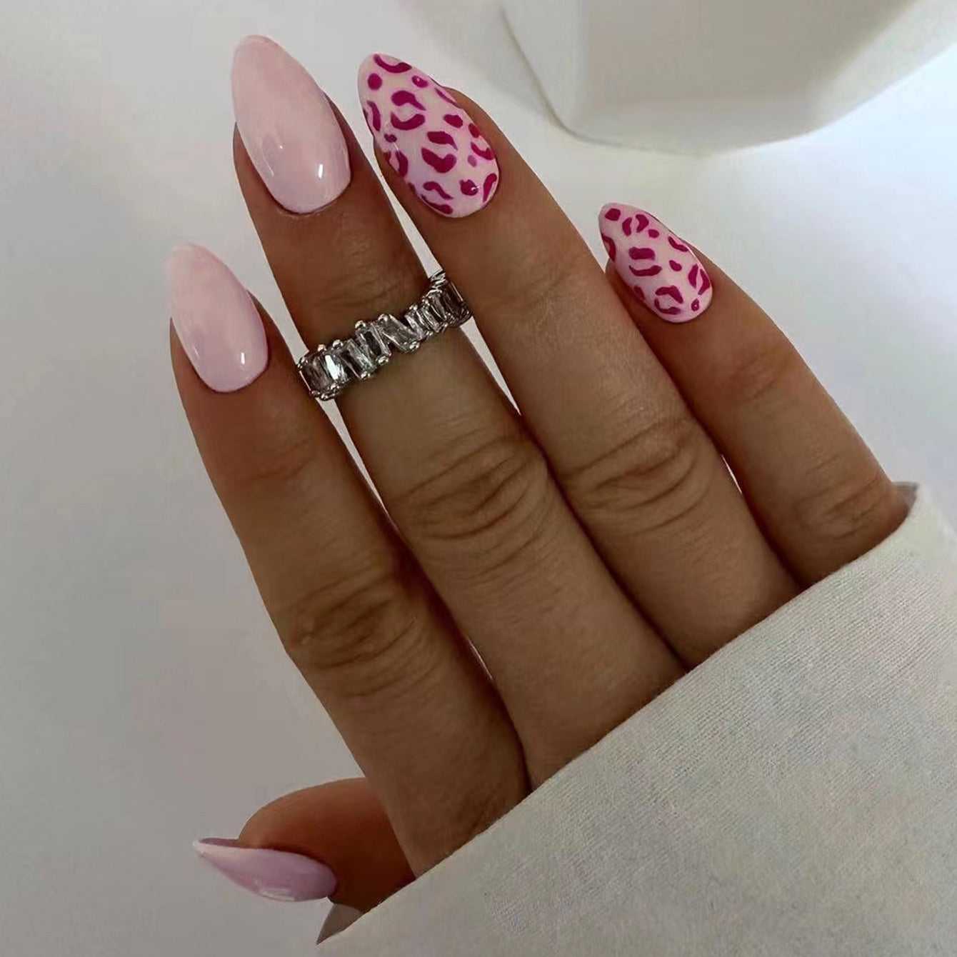 Hand with pink and leopard print nails on a plain background